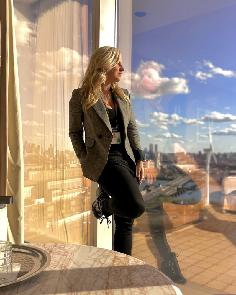 Allie at a conference, looking out a window over the city